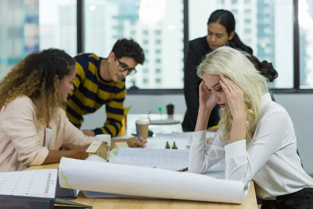 Stressed woman working with colleagues in office