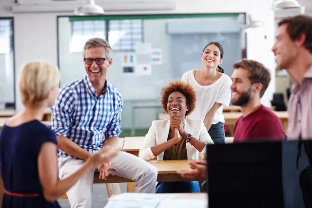 A diverse group of colleagues laughing together around a table